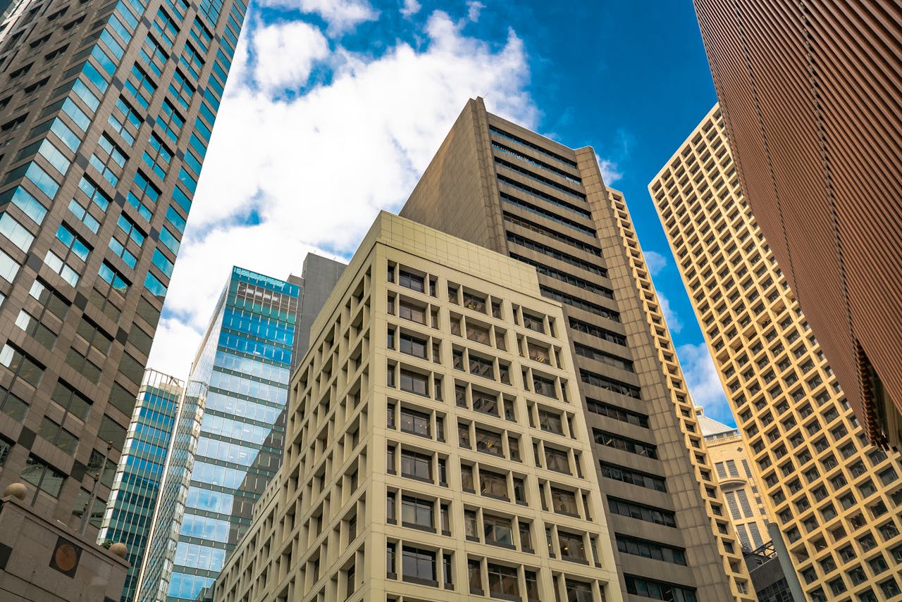 Low angle view of diverse skyscrapers in Hong Kong under a bright sky.